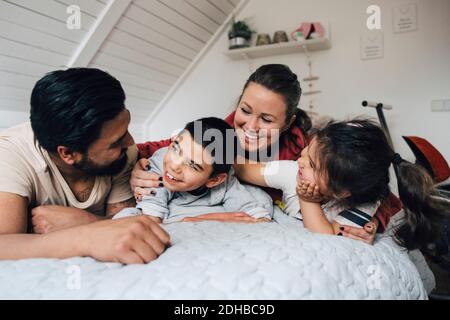 Glückliche Familie reden, während auf dem Bett zu Hause liegen Stockfoto