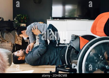 Seitenansicht des Vaters, der autistischen Sohn spielt, während er auf dem Kind liegt Boden zu Hause Stockfoto