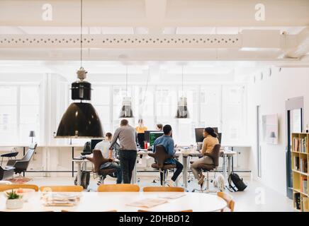 Weibliche und männliche Computerprogrammierer diskutieren am kreativen Arbeitsplatz Stockfoto