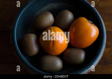 Kiwis und Kaki-Früchte in einer Schüssel Stockfoto