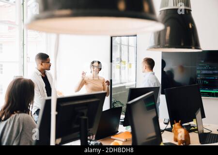 Computerprogrammierer diskutieren, während sie im kreativen Büro stehen Stockfoto