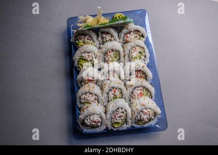 Plastikbehälter mit frisch zubereiteter Sushi-Rolle aus dem Lebensmittelgeschäft Mit Sojasauce Wasabi und Ingwer für die Seiten Oben in der Verpackung Nahaufnahme Stockfoto