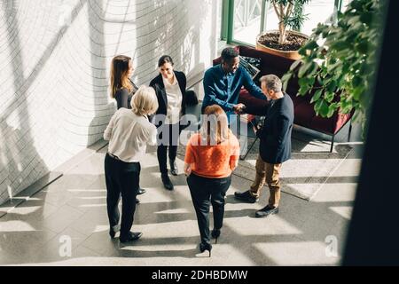 Blick aus der Perspektive auf die Begrüßung von mehrethnischen Geschäftsleuten bei der Konferenz Stockfoto