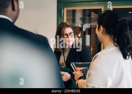 Lächelnde Geschäftsfrau im Gespräch mit Kollegen im Büro Stockfoto