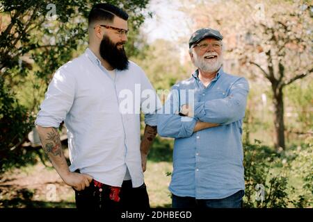 Lächelnder älterer Vater und Sohn stehen im Hof Stockfoto