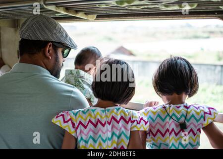 Yangon, Myanmar - 31. Dezember 2019: Eine Familie blickt vom traditionellen Kreiszug in Yangon auf den Blick Stockfoto