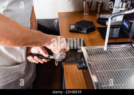 Teilweise Ansicht des Barista, der Kaffee in einem Portafilter neben dem Kaffee presst Maschine Stockfoto