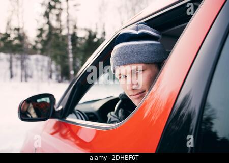 Porträt eines mittleren erwachsenen Mannes, der in einem roten Auto sitzt Stockfoto