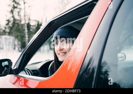 Porträt einer lächelnden Frau, die im roten Auto sitzt Stockfoto