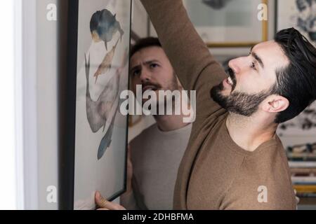 Junge Gay paar hängen Malerei an der Wand zu Hause Stockfoto