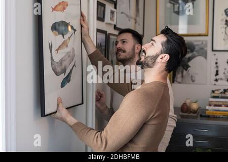 Homosexuelles Paar hängende Malerei an der Wand zu Hause Stockfoto