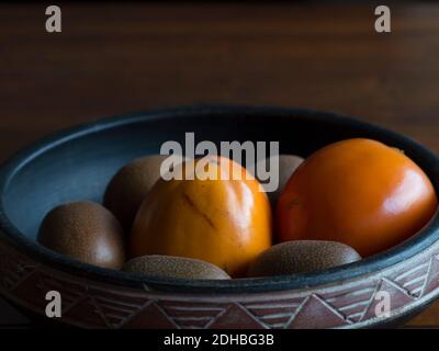 Kiwis und Kaki-Früchte in einer Schüssel Stockfoto