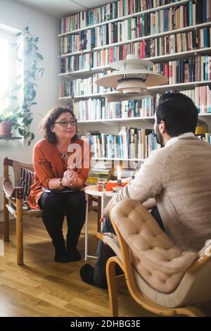 Weibliche Therapeutin, die jungen Patienten von Bücherregal zu Hause zuhören Büro Stockfoto