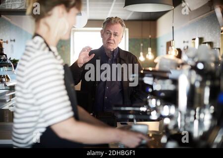 Männlicher Gast bestellt weibliche Barista am Cafe-Schalter Stockfoto