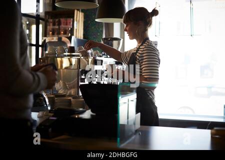 Barista bereitet Kaffee zu, während der Gast am Schalter steht Stockfoto