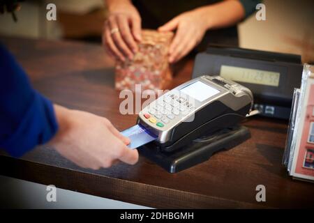 Zugeschnittenes Bild des Kunden, der an der Kasse mit Kreditkarte bezahlt Zähler Stockfoto