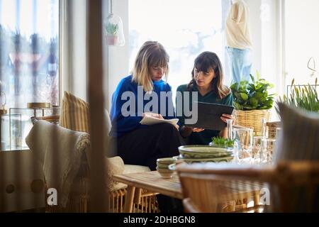 Weibliche Besitzer diskutieren über digitale Tablette in der Boutique Stockfoto