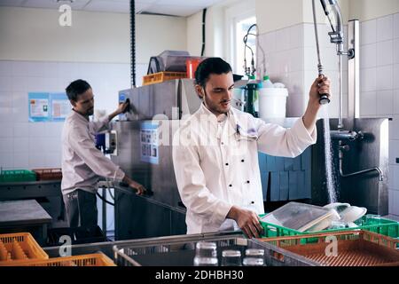 Koch sprüht Wasser auf Teller, während Kollege in der kommerziellen Arbeit Küche Stockfoto