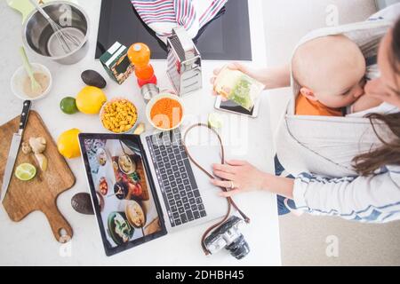 Aus der Perspektive der weiblichen Influencer-Food-Blogging während des Stillens Baby Mädchen in der Küche Stockfoto
