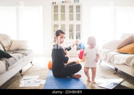 Seitenansicht der mittleren erwachsenen weiblichen Eltern, die die Tochter betrachten Während des Trainings im Home Office Stockfoto
