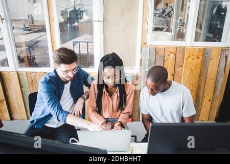 High-Angle-Ansicht von jungen professionellen Hackern diskutieren über Laptop Beim Programmieren am kreativen Arbeitsplatz Stockfoto