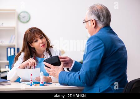 Alter Geschäftsmann besucht junge Ärztin Stockfoto