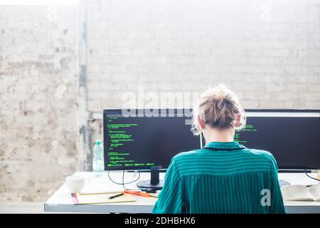 Rückansicht der jungen weiblichen Computerprogrammiererin, die am Schreibtisch arbeitet Im Büro Stockfoto