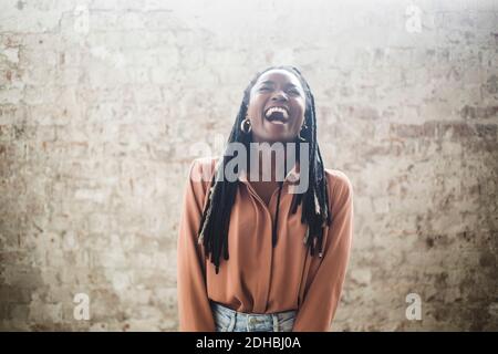 Computerhackerin mit Dreadlocks, die im Büro gegen die Wand lachen Stockfoto