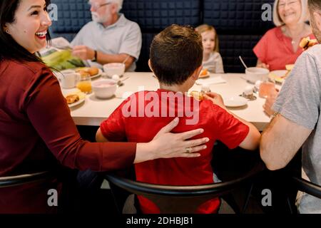 Lächelnde Frau schaut weg, während die Familie beim Frühstück sitzt Restaurant Stockfoto