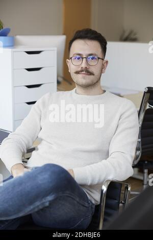 Porträt des selbstbewussten Geschäftsmann sitzt auf Stuhl im Büro Stockfoto
