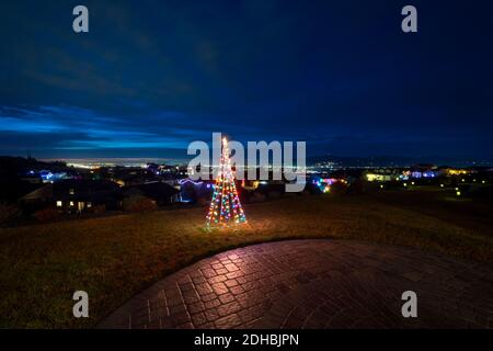 Ein beleuchtetes Weihnachtsschmuck sitzt auf einem Hügel Terrasse mit Blick auf das Spokane Valley und die Innenstadt in Washington State, USA Stockfoto