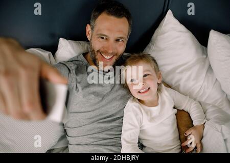 High-Angle-Ansicht des glücklichen Vaters, der Selfie mit einem Lächeln macht Tochter im Hotel im Bett Stockfoto