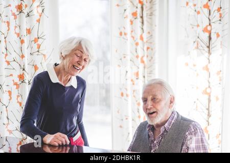 Älterer Mann, der Klavier spielt, während Frau im Pflegeheim singt Stockfoto