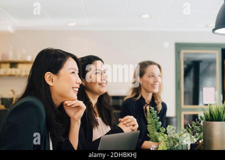 Lächelnde Geschäftsfrauen sitzen am Konferenztisch in der Sitzung Stockfoto