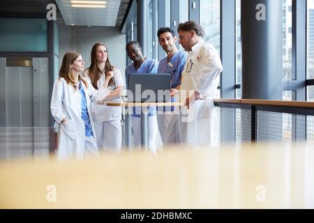 Selbstbewusste Mitarbeiter im Gesundheitswesen diskutieren über Laptop auf dem Tisch im Flur Im Krankenhaus Stockfoto