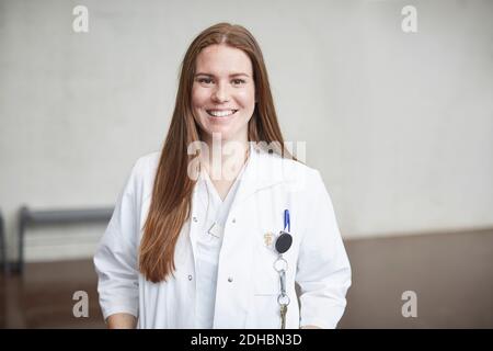 Portrait von lächelnd junge weibliche Brünette Arzt im Korridor stehen Im Krankenhaus Stockfoto