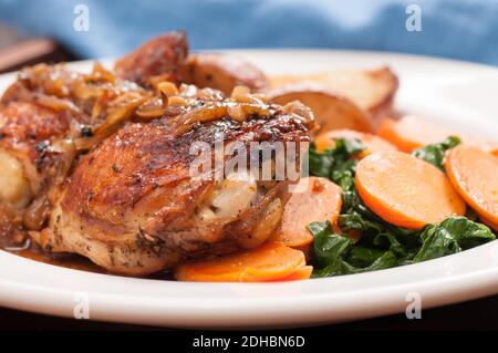 Saftig gegrillte Hähnchenschenkel mit Kartoffeln und Karotten und Spinat Stockfoto