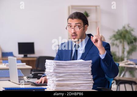 Junger männlicher Angestellter mit Skeletten im Büro Stockfoto