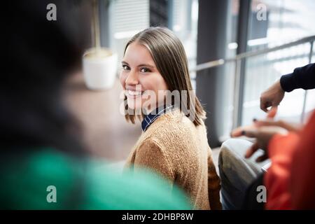 Lächelnder junger Student, der mit Freunden in der Universität sitzt Stockfoto