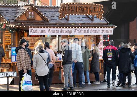 Am ersten Dezemberwochenende während der Coronavirus-Pandemie stehen Menschen an einem deutschen Wurststand im Stadtzentrum Schlange. Normalerweise hat der Weihnachtsmarkt immer an diesem Wochenende stattgefunden, aber aufgrund von Coronavirus-Einschränkungen mit Lincoln in Tier 3 wurde der Markt gestrichen. Stockfoto