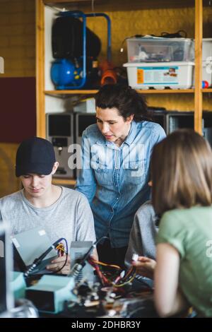 Reife Frau Lehrer Blick auf männliche High School Student Vorbereitung Wissenschaftliches Projekt im Klassenzimmer Stockfoto