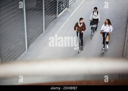 High-Angle-Ansicht der Teenager-Freunde Reiten Elektro-Push-Scooter Und Fahrrad auf der Straße in der Stadt Stockfoto