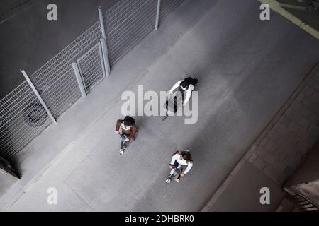 High-Angle-Ansicht von männlichen und weiblichen Freunden Reiten elektrisch Roller und Fahrrad auf der Straße in der Stadt Stockfoto