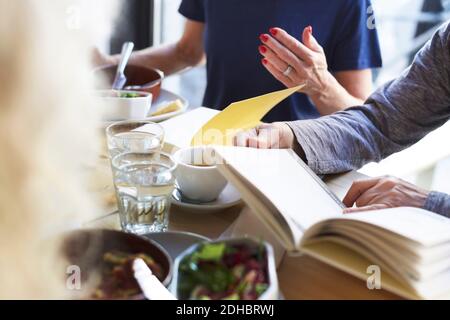 Ältere Freunde genießen das Essen im Buchclub im Restaurant Stockfoto