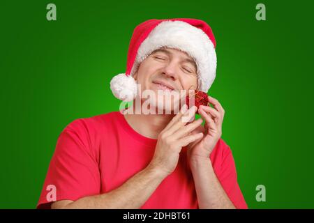 Zufrieden in Santa Hut erhalten Weihnachtsgeschenk, hält in der Nähe seines Gesichts und lächelnd Stockfoto