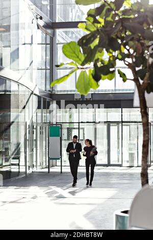 Geschäftskollegen sprechen beim Gehen im Atrium im Büro Stockfoto