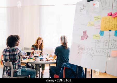 Multiethnische Geschäftskollegen, die an einem Tisch mit Whiteboard arbeiten, in kreativer Form Büro Stockfoto