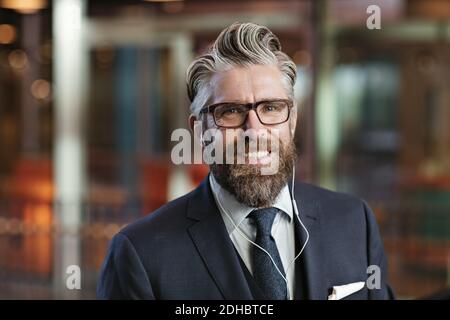 Nahaufnahme eines lächelnden Geschäftsmanns, der im Büro Kopfhörer trägt Stockfoto