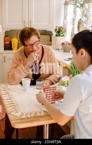 Junge Ärztin, die mit älteren Frauen über Medikamente diskutiert Am Tisch im Pflegeheim Stockfoto