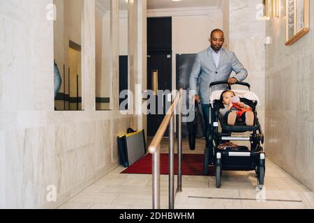 Volle Länge des Mannes schieben Mädchen in Wagen außerhalb Haus Stockfoto